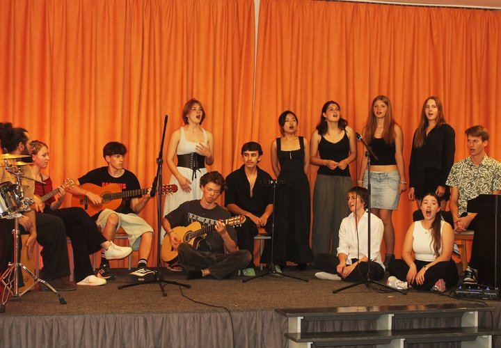 Das Foto zeigt junge Frauen und Männer singend auf einer Bühne.