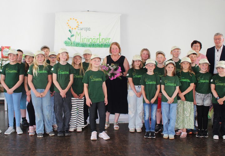 Mehrere Kinder in grünen T-Shirts, die Projektleiterin Marlies Böttcher, Bürgermeister Andreas Burger und die ehemalige Bürgermeisterin Steffi Trittel lächeln gemeinsam in die Kamera.