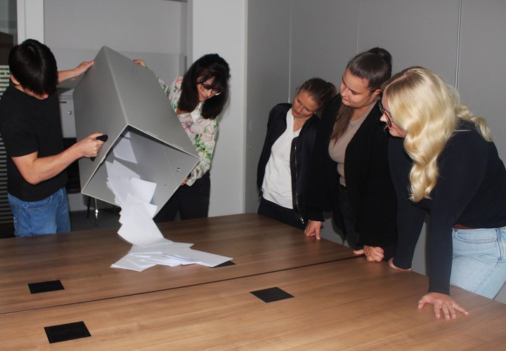 Vier Frauen und ein Mann leeren eine Wahlurne.