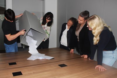 Vier Frauen und ein Mann leeren eine Wahlurne.