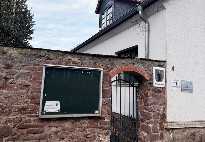 Mauer mit Tür und einem Haus dahinter