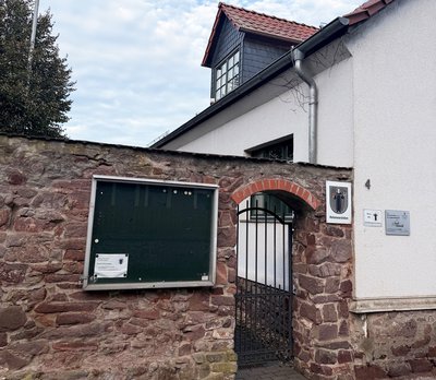 Mauer mit Tür und einem Haus dahinter