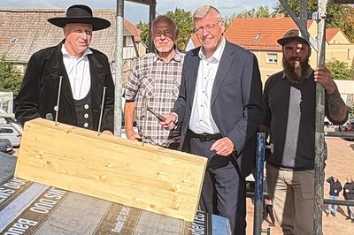 Vier Männer wollen beim Richtfest die Nägel einschlagen.