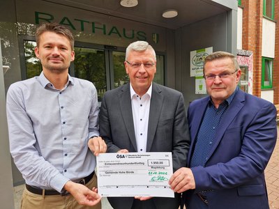 Drei Männer halten einen symbolischen Scheck.