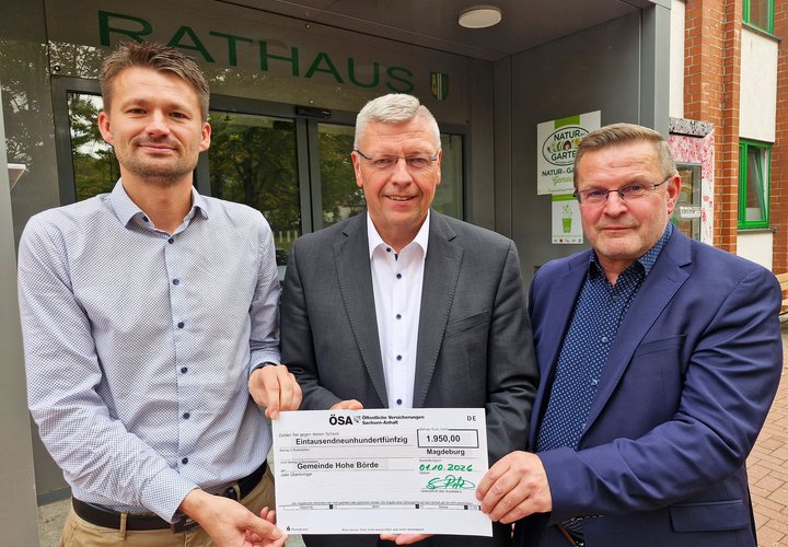 Drei Männer halten einen symbolischen Scheck.